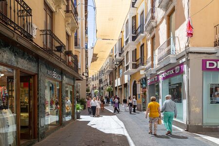 Granada, Spain - May 27, 2019: People walking in a charming narrow shopping street in the historic city centre.のeditorial素材