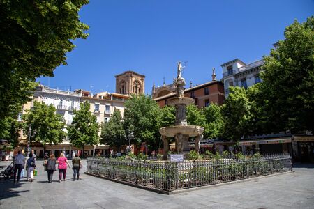 Granada, Spain - May 27, 2019: People walking past a fountain on Bib Rambla Square in the historic city centre.のeditorial素材