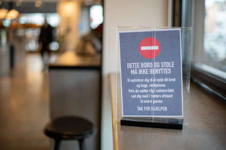 Copenhagen, Denmark - March 17, 2020: A sign in a cafe informing about closed tables and minium...