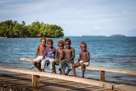 Chea Vilalge, Solomon Islands - June 15, 2015: Group of kids sitting on a wooden pierのeditorial素材