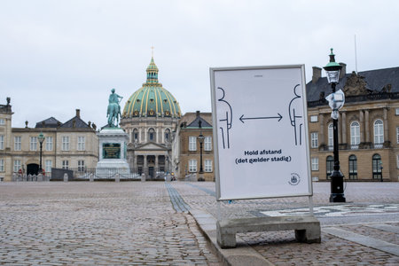 Copenhagen, Denmark - December 31, 2020: Sign on Amalienborg Palace Square reminding people to keep distance to each other due to corona virus.のeditorial素材
