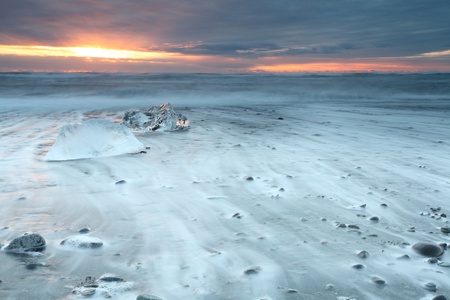 Ice on vocanic black sand iceland beach at sunsetの写真素材
