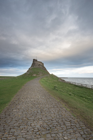 Dawn breaks over Lindisfarne Castle on Holy Island Northumberland with the stars and Milky Way still overhead in the fading night sky.のeditorial素材