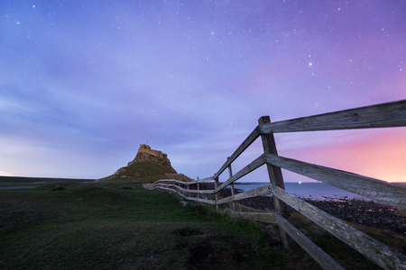 Dawn breaks over Lindisfarne Castle on Holy Island Northumberland with the stars and Milky Way still overhead in the fading night sky.のeditorial素材