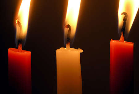 three burning candles: two red and a white one        