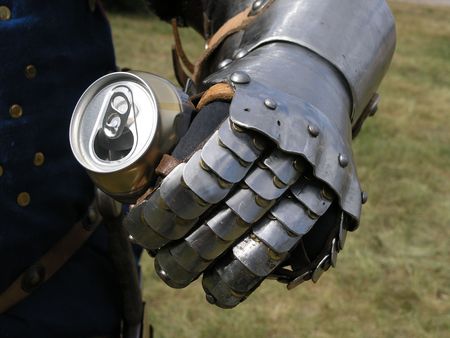 hand of a medieval knight wearing metal armour squeezing a tin  の写真素材