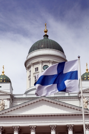 fluttering national flag of Finland against Helsinki Cathedral, most prominent building and symbol of the cityの写真素材