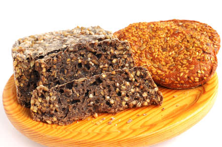 homemade brown bread and buns with sesame seeds on wooden cutting board 
