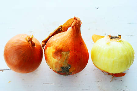 three onions on a white table, horizontalの写真素材