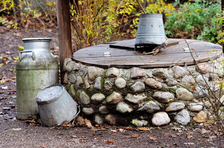 rustic stone well, can and bucket in the gardenの写真素材