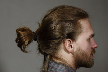portrait of a young man with a beard and mustache side on dark backgroundの写真素材