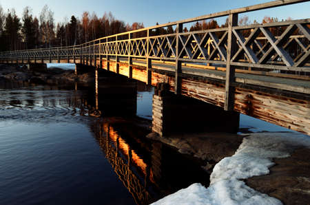 old wooden bridge over the river at sunset in winter