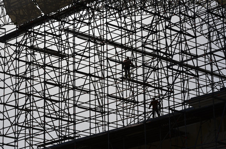 workers assemble metal construction on blue sky backgroundの写真素材