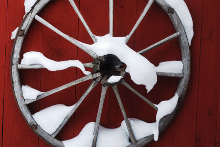 wooden wheel on the red wall with snowの写真素材