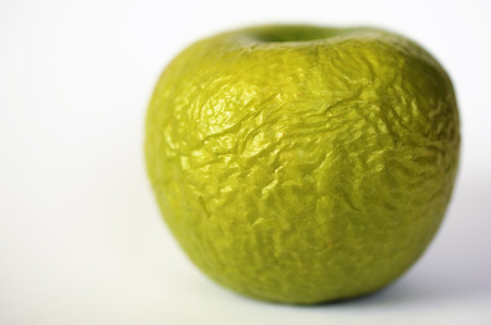 contracted green dry apple against white background
