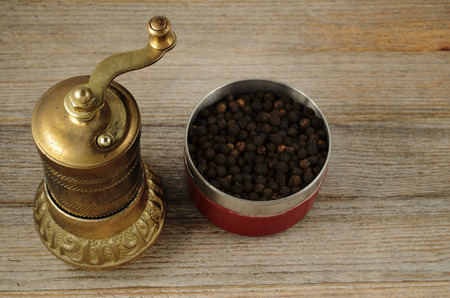 old oriental pepper mill and black pepper peas on wooden backgroundの写真素材