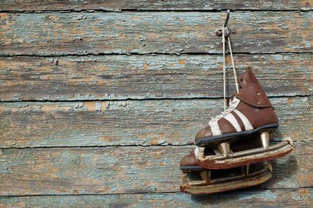 vintage pair of mens  ice skates hanging on a cracked paint wallの写真素材