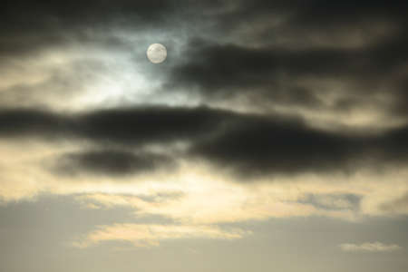 gloomy winter sky with gray clouds and sun