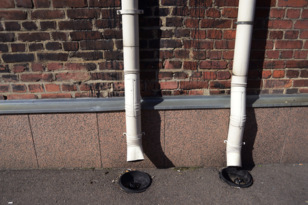 two old drainpipes on a brick wall background