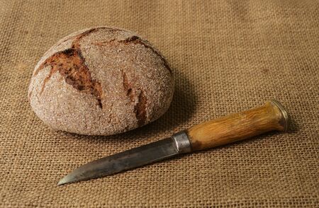 circle of traditional finnish rye bread on burlap and finnish knife puukkoの写真素材