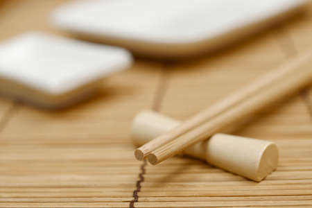 japanese chopsticks on stand, bamboo mat and sushi dishesの写真素材