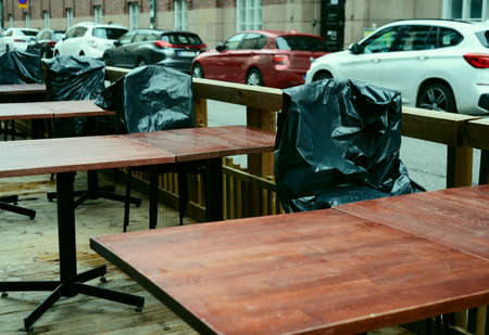 summer is over, plastic-covered chairs in empty street cafe, filter appliedの写真素材