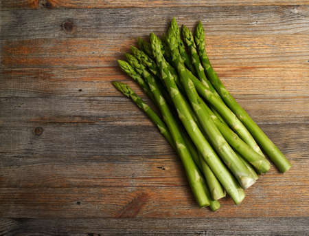 a bunch of asparagus on a wooden background with room for textの写真素材