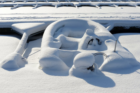 boat with outboard motor covered with snow in winter at the boat parkingの写真素材