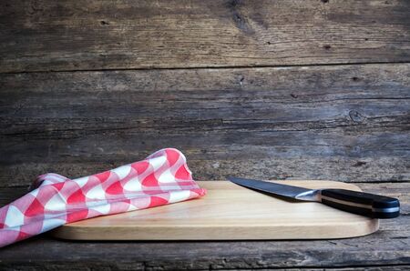Empty chopping board with a sharp paring knife and napkin on a distressed grunge wooden tableの写真素材