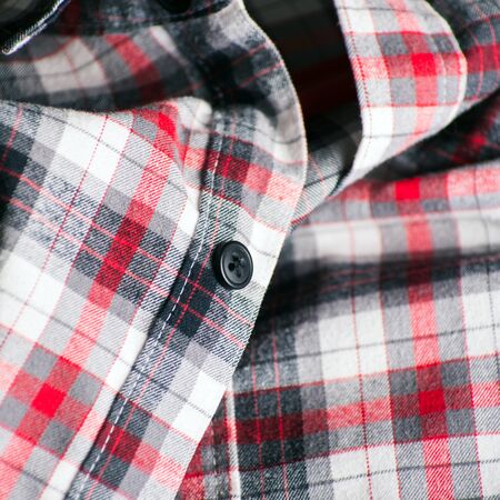 Close up detail of a red plaid button up style shirt.