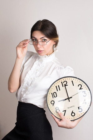 Portrait of beautiful young business woman holding in clockの写真素材