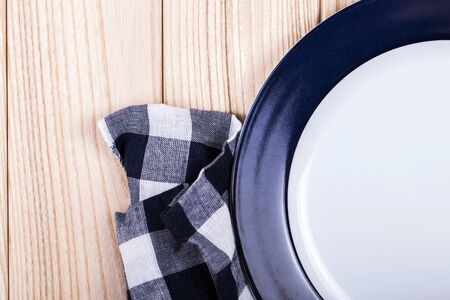 Empty dish, knife and fork and blue napkin on wood tableの写真素材