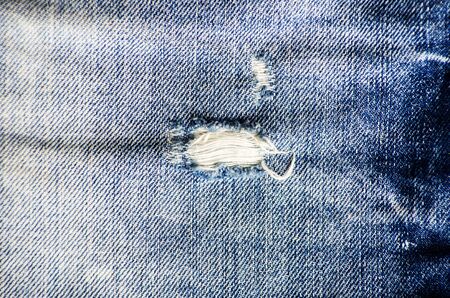 blue jean texture with a hole and threads showingの写真素材