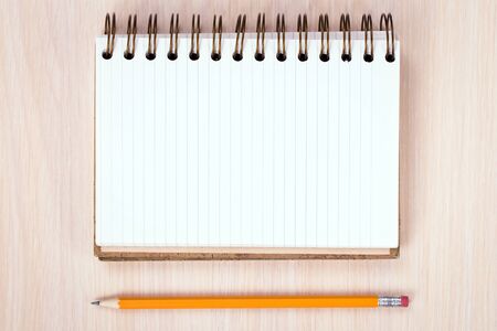 notepad with a pencil on a wooden background