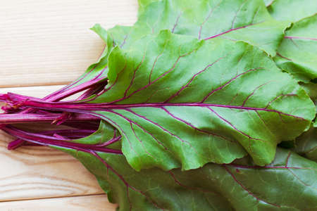 Bunch of red beet leaves on wooden backroundの写真素材