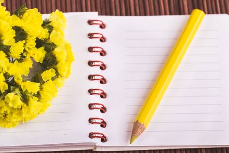 flowers notebook and pencil on wooden backgroundの写真素材