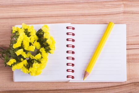 flowers notebook and pencil on wooden backgroundの写真素材