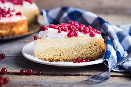 cheesecake with fresh red currants on a thin wooden background