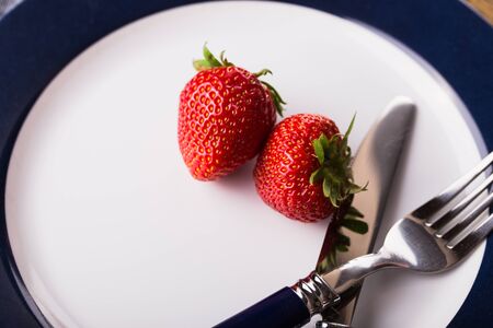 strawberries on a plate with knife and fork on wooden backgroundの写真素材
