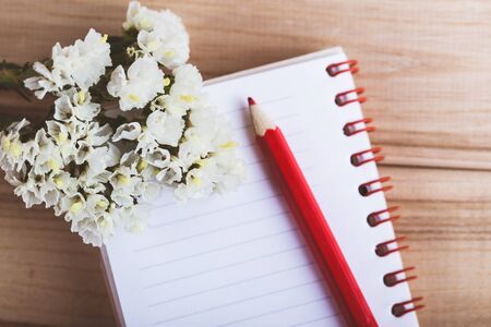 flowers notebook and pencil on wooden backgroundの写真素材