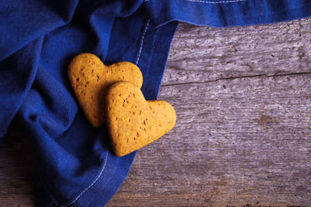 cookies in the shape of a heart on a wooden background with a blue clothの写真素材