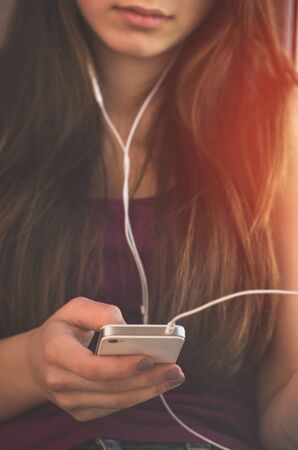 young girl with a phone in his hands listening to music on headphonesの写真素材