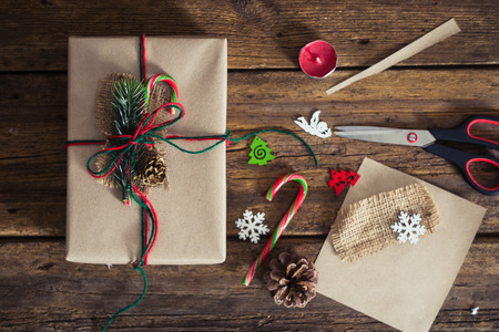 Christmas gift box on a wooden background with candy cane, fir branches, candle, cones.の写真素材