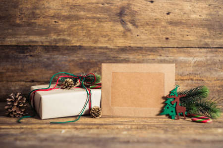 Christmas gift box with cards  on a wooden background with candy cane, fir branches, candle, cones.の写真素材