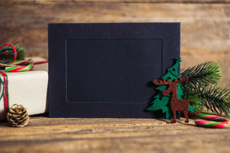 Christmas gift box with cards  on a wooden background with candy cane, fir branches, candle, cones.の写真素材