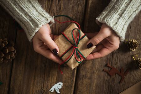 Male hands wrapping xmas gifts into paper and tying them up with red threadsの写真素材