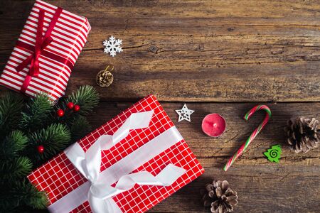 Christmas presents on a wooden background with candy cane, fir branches, candle, cones.の写真素材