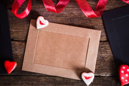 Gift Cards on wooden background with cookies in the shape of heart and red ribbon
