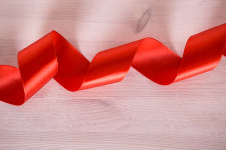Red satin ribbon on a white wooden background