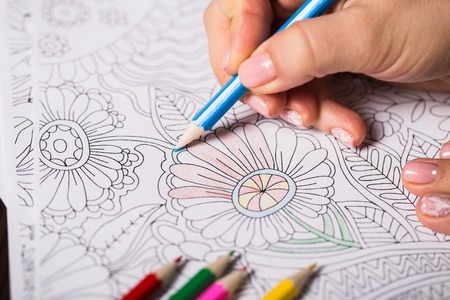 Girl paints a coloring book for adults
